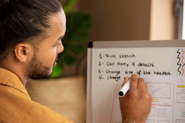 A man writing goals on a whiteboard, illustrating effective goal setting strategies and techniques for success.