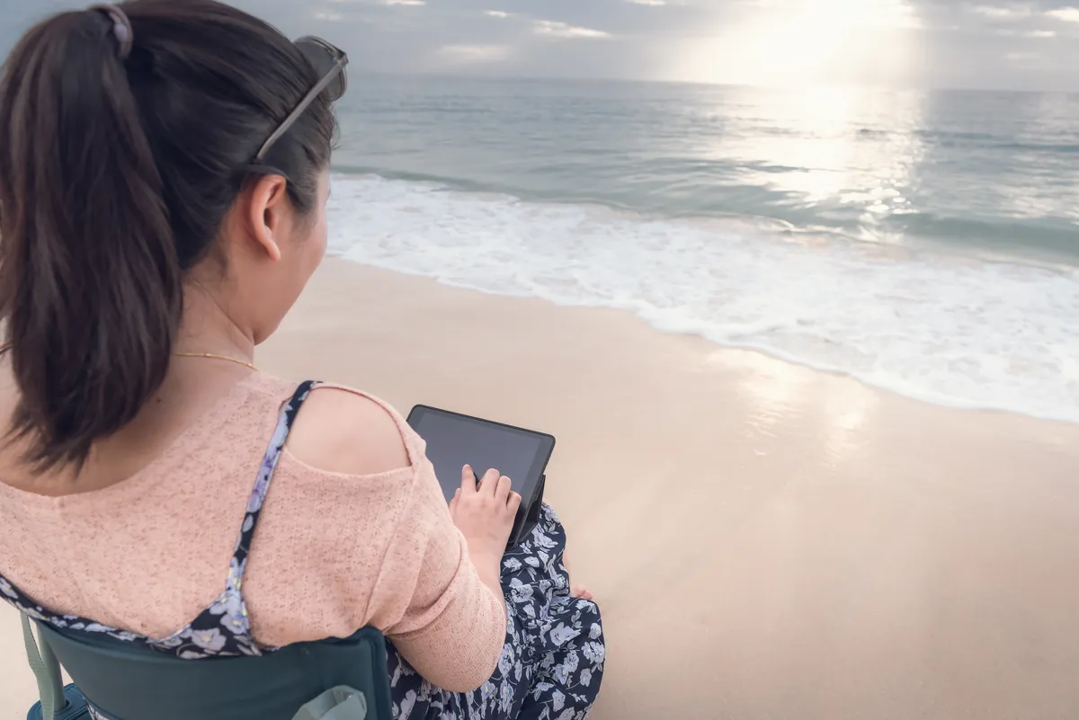 Woman sitting by the sea writing down thoughts to create clarity and calm a busy mind