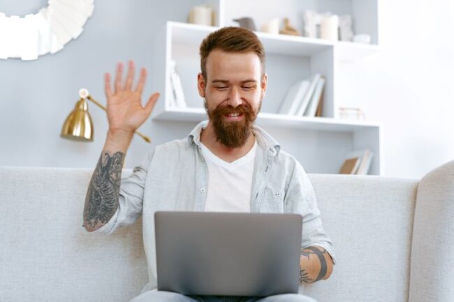 A man receiving online therapy on a laptop, illustrating the concept of remote counselling and coaching.