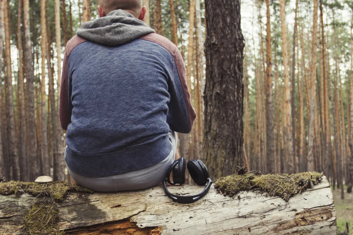 Man sitting alone in woodland reflecting on stress, support and emotional wellbeing