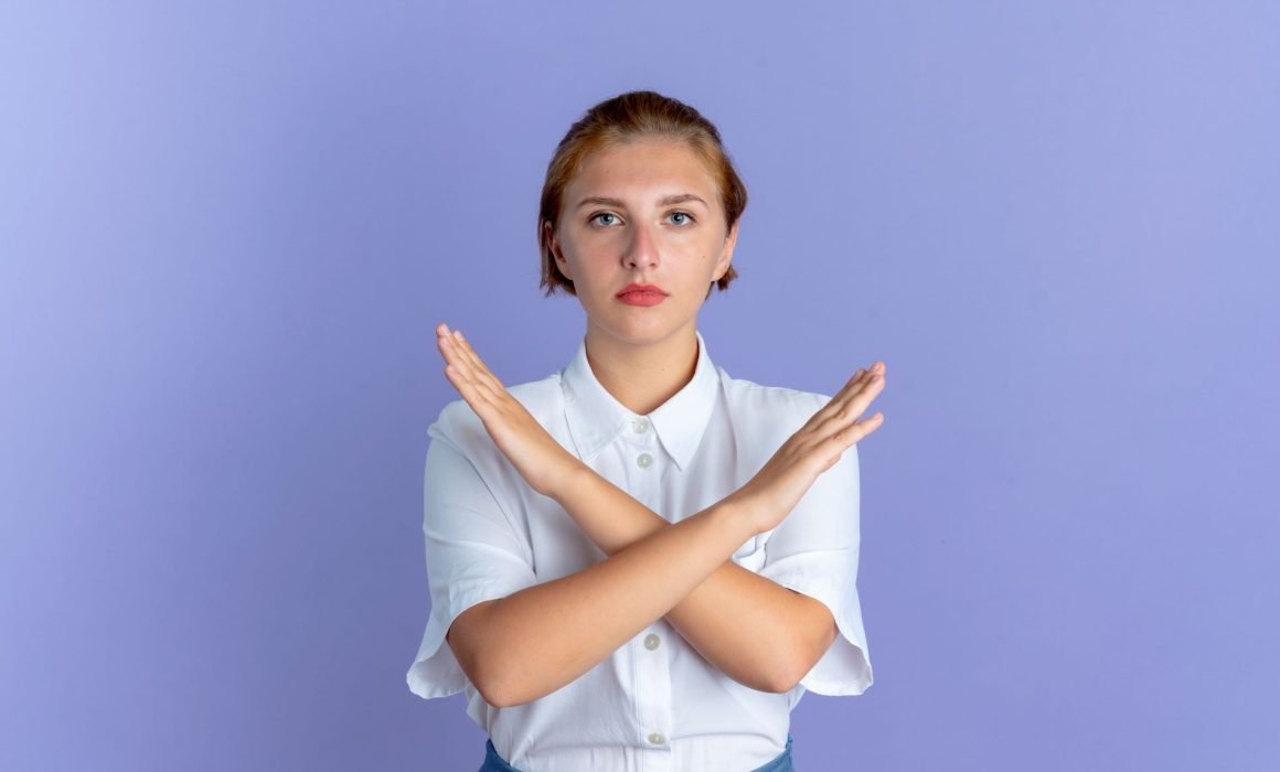 A woman with her arms crossed and a confident expression, representing the act of saying no and setting boundaries to stop being a people-pleaser