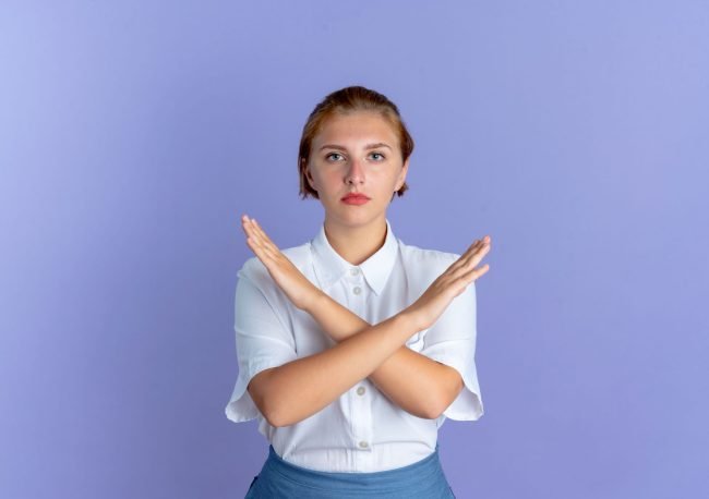 A woman with her arms crossed and a confident expression, representing the act of saying no and setting boundaries to stop being a people-pleaser