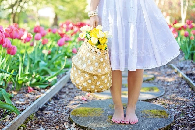 Woman standing barefoot on stone with flowers, reflecting grounding techniques.