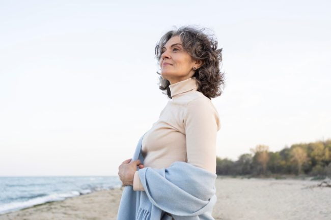Mature woman enjoying a peaceful moment on the beach, symbolising calm and empowerment in managing menopause and ADHD