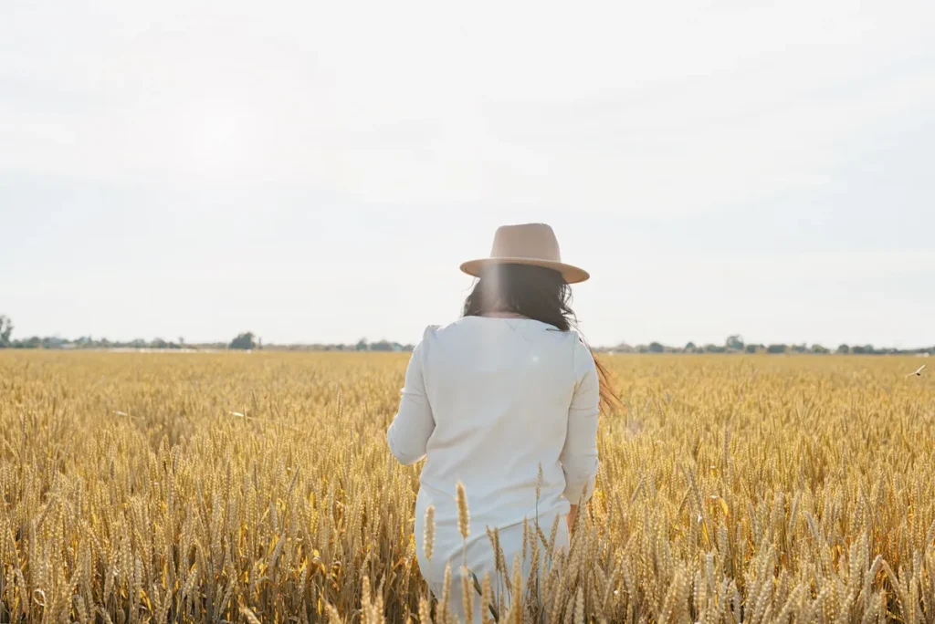 Woman standing in a wheat field reflecting on changes in confidence, energy and wellbeing