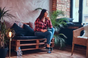 Woman sitting thoughtfully by a window reflecting on motivation and personal goals