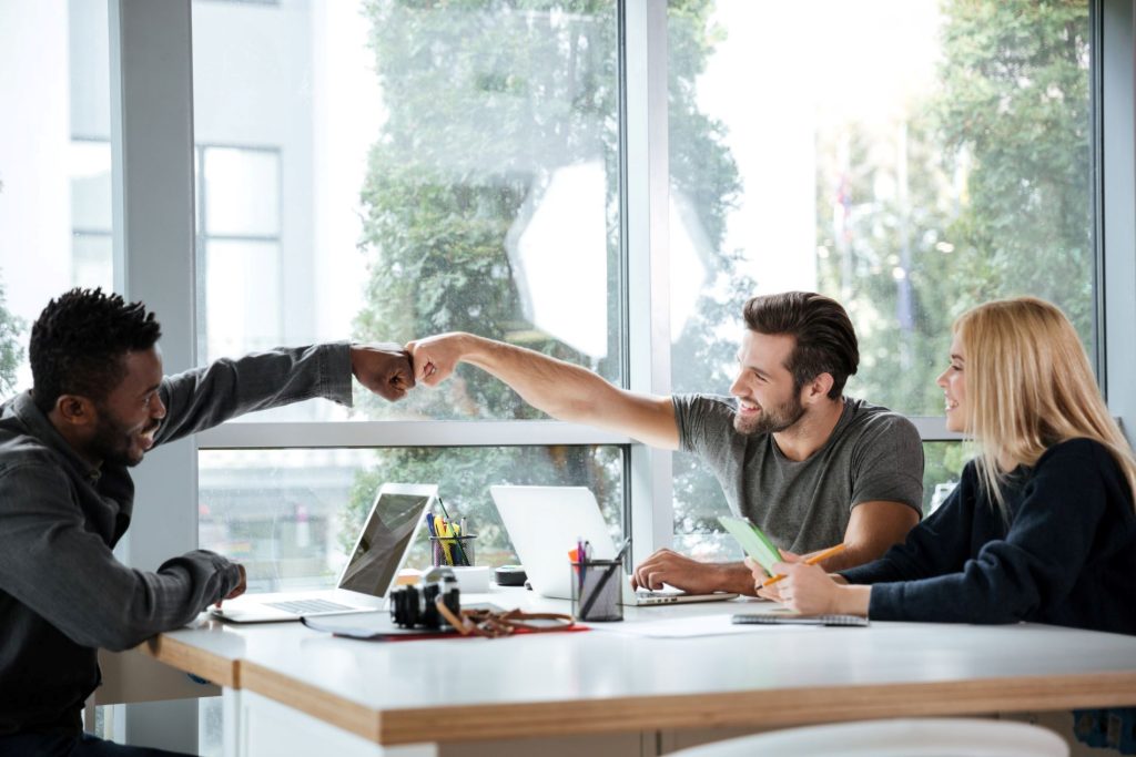Colleagues fist bumping and looking happy