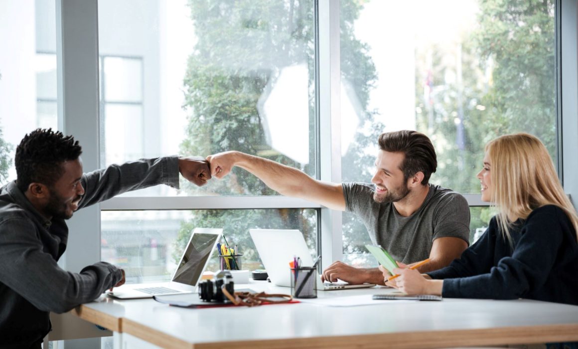 ADHD coaching in workplace dynamics - colleagues fist bumping, fostering teamwork and positivity.