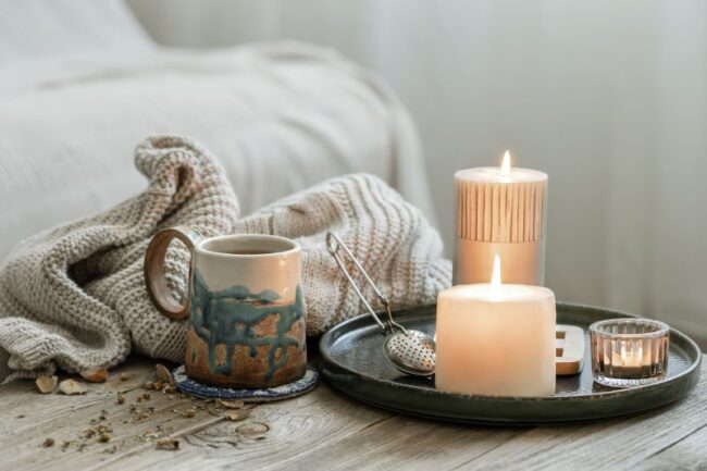 cozy composition with mug, candles and a blanket representing grounding exercises