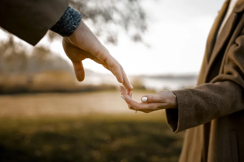 Elderly couple holding hands warmly in an autumn park surrounded by golden leaves