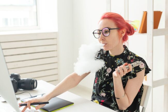 Woman sitting at her work desk vaping reflecting on stopping vaping