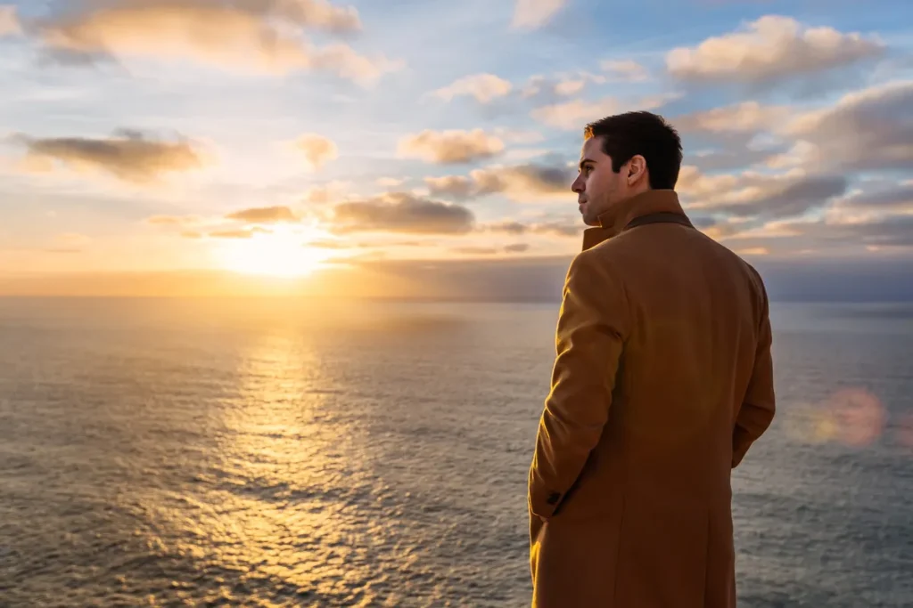 Man standing by the sea at sunset reflecting on uncertainty and the future