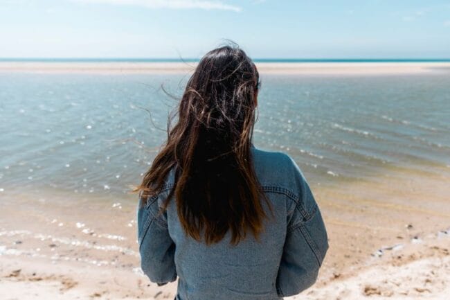 woman standing on the beach looking out into the sea reflecting on goals