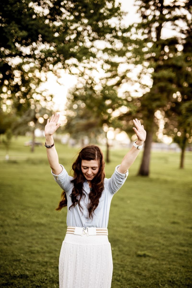 Feeling free and empowered after overcoming phobias A woman in a white outfit with long hair stands in the countryside, lifting her hands in the air in a moment of freedom and confidence.