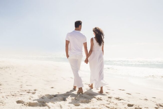 A couple walking hand in hand along the beach, symbolising connection, trust, and emotional support in relationships.