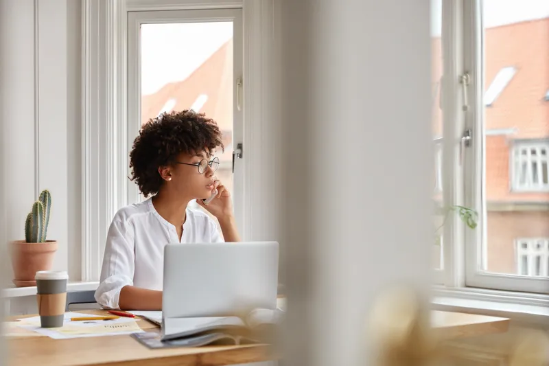 Woman sitting by a window looking out thoughtfully