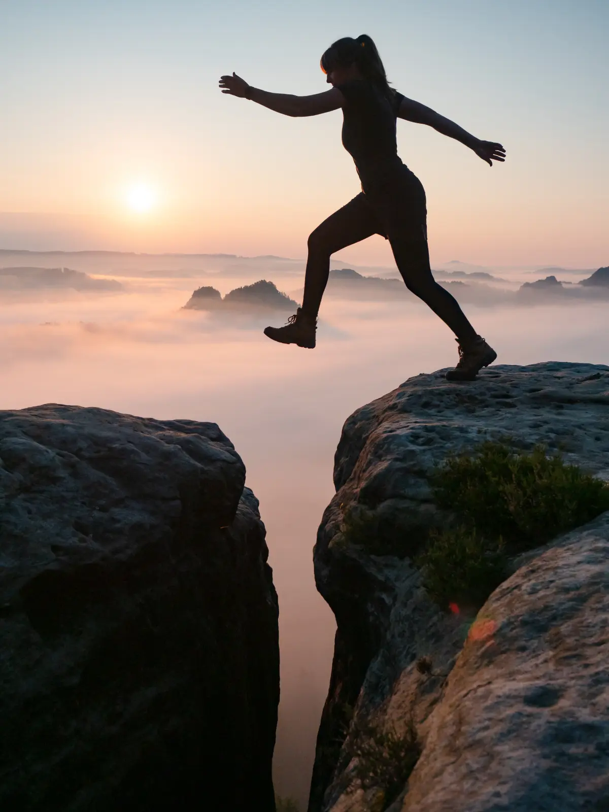 Woman taking a leap over two large stones