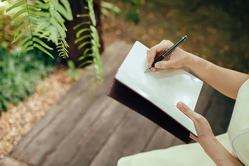 Close up of a hand writing carefully in a notebook with a pencil