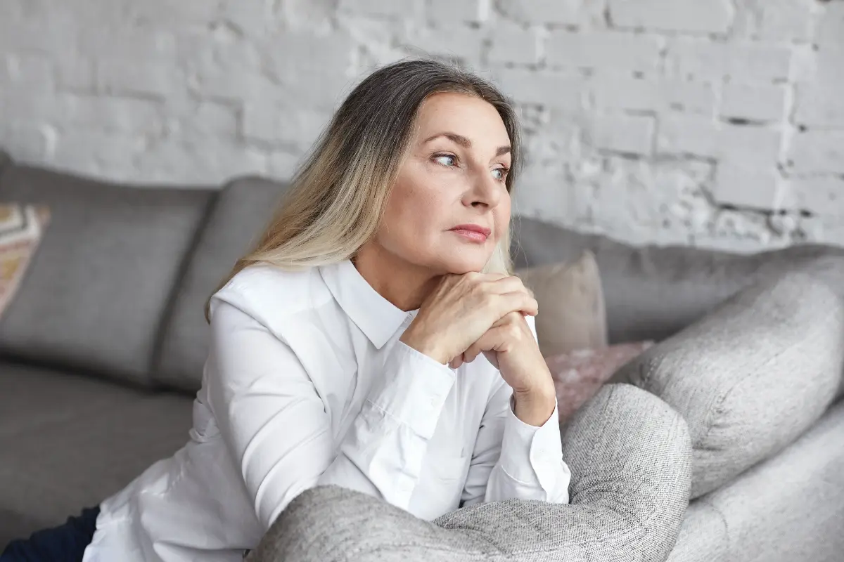 Woman sitting indoors in a quiet moment, reflecting as her thoughts wander during a calm pause
