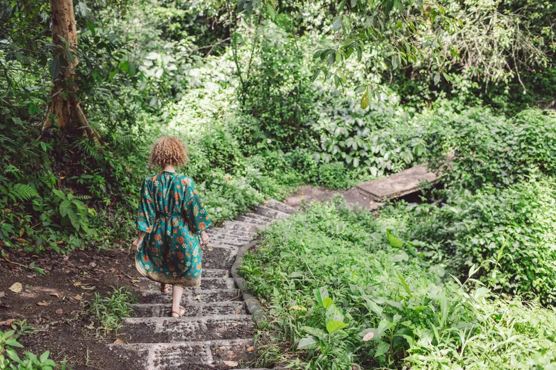 Woman walking down a woodland path taking one step at a time during a period of change