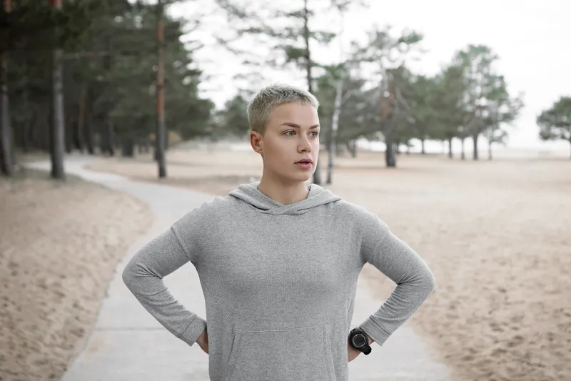 Sporty woman standing outdoors with her hands on her hips during a quiet pause