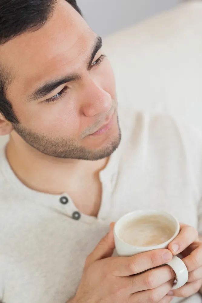A man sitting quietly with a coffee, reflecting, representing the emotional side of ADHD explored in ADHD-informed therapy at Clear Haven Therapy