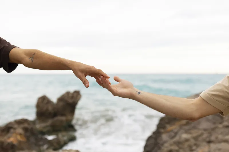 Two people gently touching fingertips outdoors in soft golden light