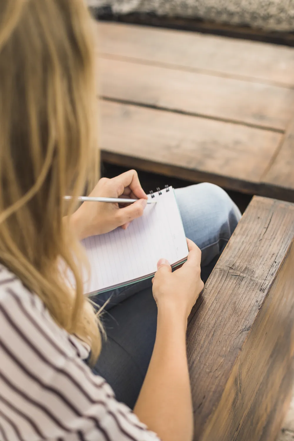 Woman writing in a notebook during ADHD-informed therapy reflection.