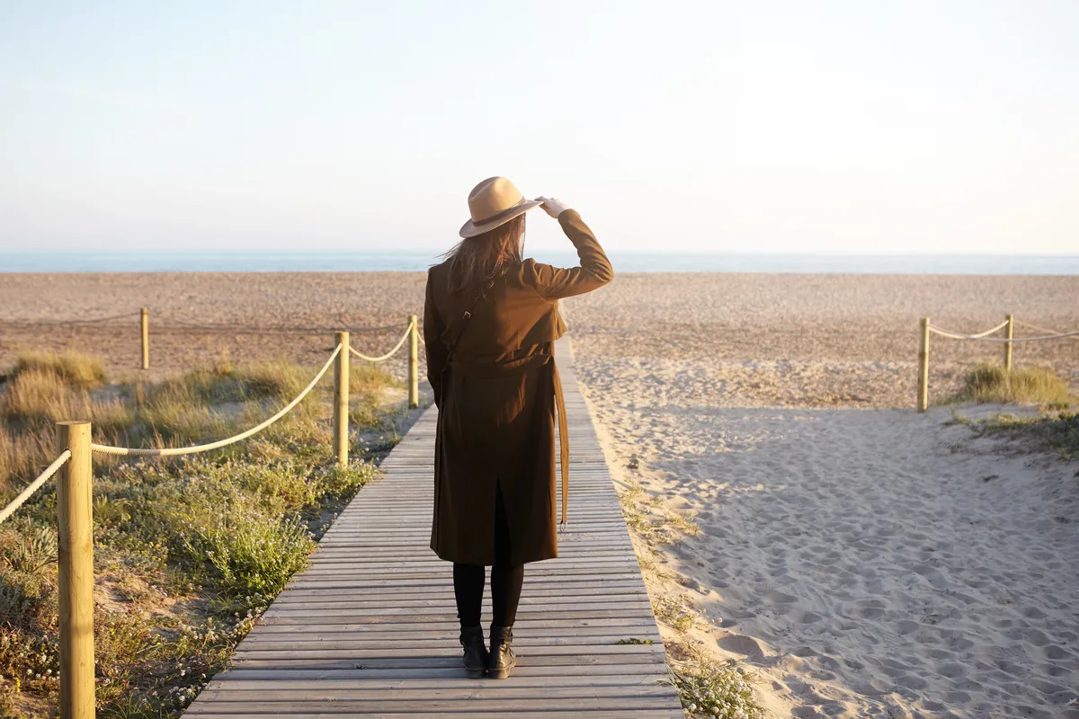 Woman walking along a beach boardwalk representing ADHD-informed therapy and personal reflection.