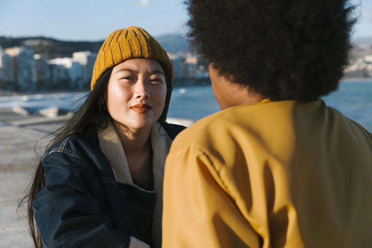 Two people having a conversation outdoors, with one woman looking intently at the other.